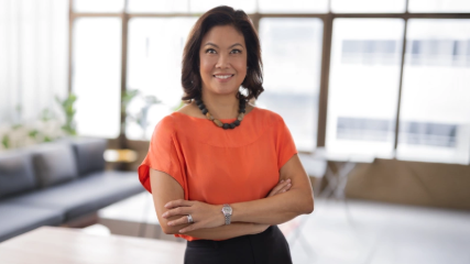 Woman with orange top standing with crossed arms